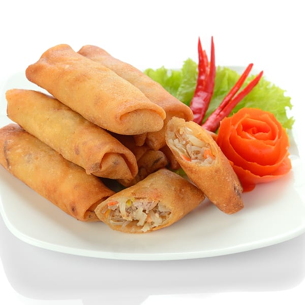 Crispy Japanese spring rolls, one cut open to show filling, garnished with lettuce, red chilies, and a tomato rose.