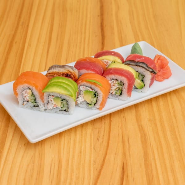 A white rectangular plate filled with various colorful sushi rolls, including salmon, tuna, and avocado.