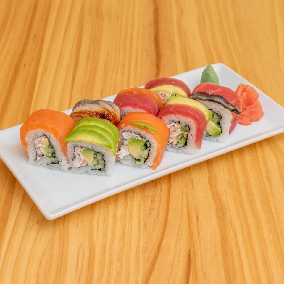 A white rectangular plate filled with various colorful sushi rolls, including salmon, tuna, and avocado.